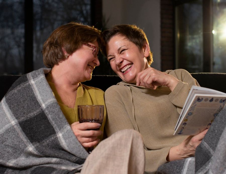 Dos mujeres mayores disfrutan una tarde juntas, riendo en el sillón